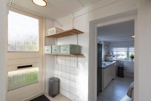 cocina con paredes blancas, ventana y puerta en De Bunker - Callantsoog, en Callantsoog