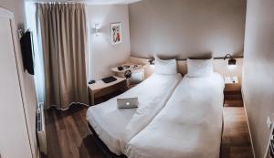 a hotel room with a bed with a laptop on it at Le Konine - Hotel & Bar & Restaurant in Montceau-les-Mines
