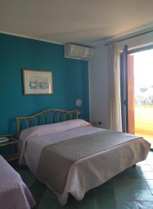 Un dormitorio con una cama con paredes azules y una ventana en Albergo Il Biancospino, en Sirmione