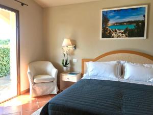 a bedroom with a bed and a chair and a window at Hotel Nibaru in Porto Cervo