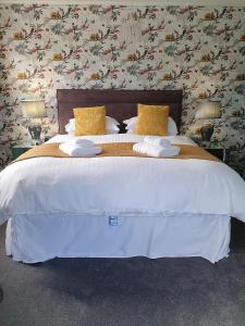 Elle comprend un grand lit avec des draps blancs et des oreillers jaunes. dans l'établissement Marley House Bed and Breakfast, à Winfrith Newburgh
