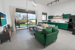 a living room with a green couch and a kitchen at סוויטת החוף אכזיב - Beach Suite Achziv in Nahariyya