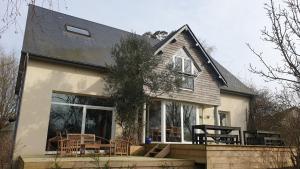 a house with a porch and chairs in front of it at Grande maison avec SPA proche de CAEN et de la mer in Brouay