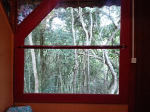 una ventana con vistas a un bosque de árboles en Vila do Mago en Itamonte