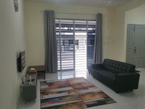 a living room with a black couch and a rug at Padang Besar Homestay in Padang Besar +4 photos