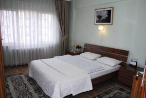 a bedroom with a large white bed and a window at ViP Apartments in Çekirge