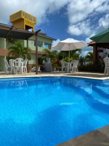 une grande piscine bleue avec des chaises et un parasol dans l'établissement Pousada Mares do Sul, à Conde