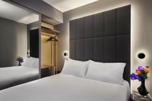 sypialnia z 2 łóżkami i dużym lustrem w obiekcie AMANO Covent Garden w Londynie