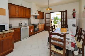 a kitchen with a dining room table and a kitchen with at Casa das Palmeiras by OCvillas in Albufeira