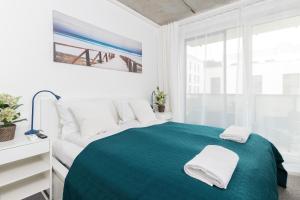 a white bedroom with a green bed and a window at Lux Family Apartment Nadmorskie Tarasy by Renters in Gdynia