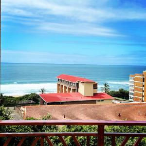 a building with a red roof next to the ocean at Victorian Beach Cottages in Amanzimtoti