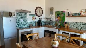a kitchen with a table and a clock on the wall at Victorian Beach Cottages in Amanzimtoti