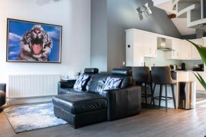 a living room with a black leather couch and a dog on the wall at Tiger Roof Terrace Lymm in Lymm