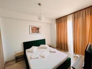 a bedroom with a bed with white sheets and a window at Summerland Studios Nuba in Mamaia