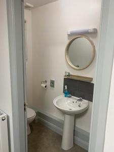 a bathroom with a sink and a mirror and a toilet at The Village Inn in Northallerton