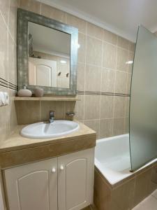 a bathroom with a sink and a mirror and a tub at OLIVA NOVA GOLF BEACH & RESORT Club Sevilla V in Oliva