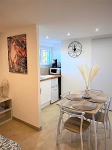 eine Küche und ein Esszimmer mit einem Tisch und einer Uhr in der Unterkunft Studio Le Plum'Art, 10mn Zoo de Beauval avec jardin in Noyers-sur-Cher