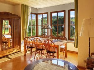 comedor con mesa, sillas y ventanas en Familienferienwohnung Villa Zaunkönigin, en Bischofsheim an der Rhön