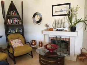 een woonkamer met een open haard, een stoel en een tafel bij Casa da Barra in Praia da Barra