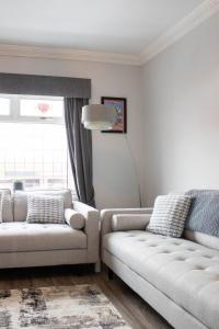 a living room with two white couches and a window at Trafford Terrace Davyhulme in Urmston