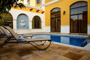 a pool with two chairs next to a house at Hotel Plaza Campeche in Campeche