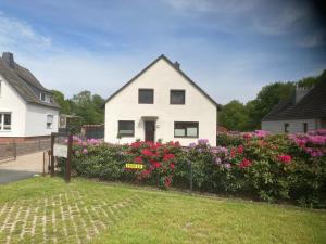 una casa bianca con fiori rosa in un cortile di Ferienwohnung Hartmann a Wehdel