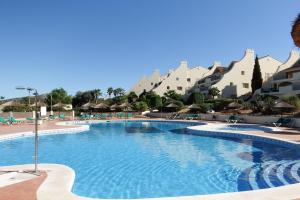 uma piscina num resort com cadeiras e guarda-sóis em La Manga Club Resort - Los Olivos 343 em Atamaría