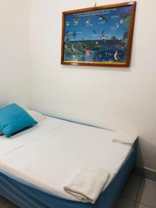 a bed in a room with a picture on the wall at Hostal Marysol in Puerto Ayora