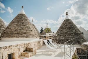 a group of pyramid turrets with a chair on a patio at Nina Trulli Resort in Selva di Fasano