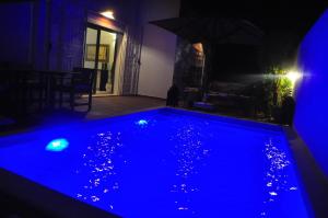 - une piscine dans une chambre sombre avec des lumières bleues dans l'établissement VILLA KENZA, à Midoun