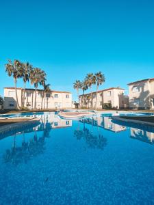 a large swimming pool with palm trees and buildings at OLIVA NOVA GOLF BEACH & RESORT club sevilla II in Oliva