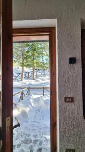 a door with a view of a snow covered yard at Appartamento immerso nella natura in Frontignano