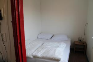 a small bed in a room with white sheets at boerderij de duinen 115 in De Cocksdorp