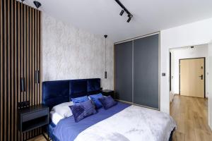 a bedroom with a large bed with a blue headboard at Apartament Marynarska Aquapark in Reda