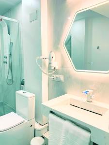 Baño blanco con lavabo y espejo en La Placita Boutique Centro, en Málaga