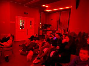 um grupo de pessoas sentadas numa sala com luzes vermelhas em Engi Panzió em Ocna de Sus