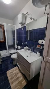 La salle de bains est pourvue d'un lavabo, de toilettes et de carrelage bleu. dans l'établissement Appartamento immerso nella natura, à Frontignano