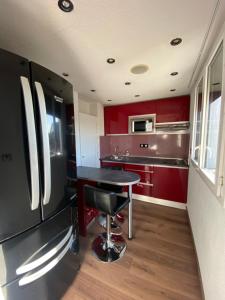 een keuken met rode kasten en een zwarte koelkast bij La Résidence Amal in Talence