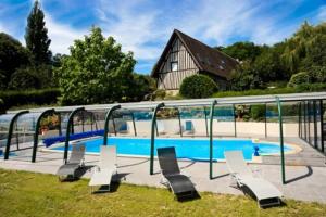 a swimming pool with lounge chairs in front of a house at Le Vieux Pressoir in Pont-lʼÉvêque