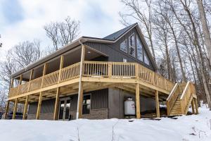 a house with a wrap around deck in the snow at NEW!! House Near Raystown Lake in Peaceful Wooded Area in Huntingdon