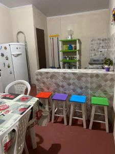una cocina con taburetes coloridos frente a un mostrador en RECANTO DO BETERRABA en Mundaú