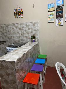 una cocina con taburetes coloridos frente a un mostrador en RECANTO DO BETERRABA en Mundaú