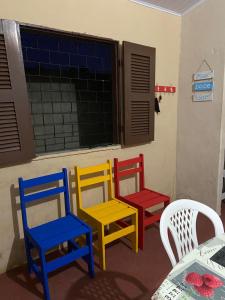 four colorful chairs in a room with a window at RECANTO DO BETERRABA in Mundaú