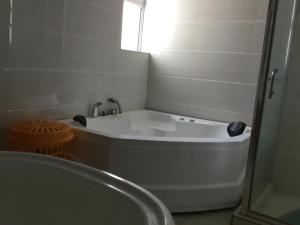 a white bath tub in a bathroom with a window at Yaya Brooks - Tomax in Nairobi