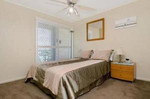a bedroom with a large bed and a window at Surfside On The Beach in Buddina