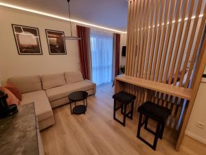 sala de estar con sofá y 2 taburetes en Apartamenty 21 Śląska, en Szczecin