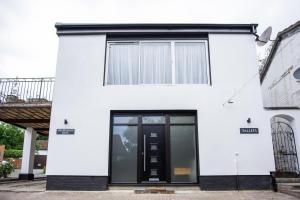 a white house with a black door at Shepherd's Rest Apartments Central Location With Parking in Tewkesbury