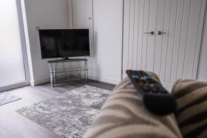 um controle remoto sentado num sofá na sala de estar em Shepherd's Rest Apartments Central Location With Parking em Tewkesbury