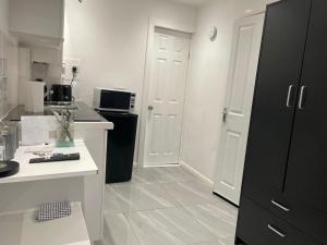 una cucina con frigorifero nero e bancone bianco di Elegant Practical onsite Cosy Studio in a quiet location a Coventry