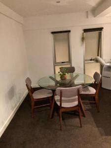 Light-Filled Converted Warehouse 2 Bedroom Apartment in Prahran في ملبورن: غرفة طعام مع طاولة وكراسي زجاجية